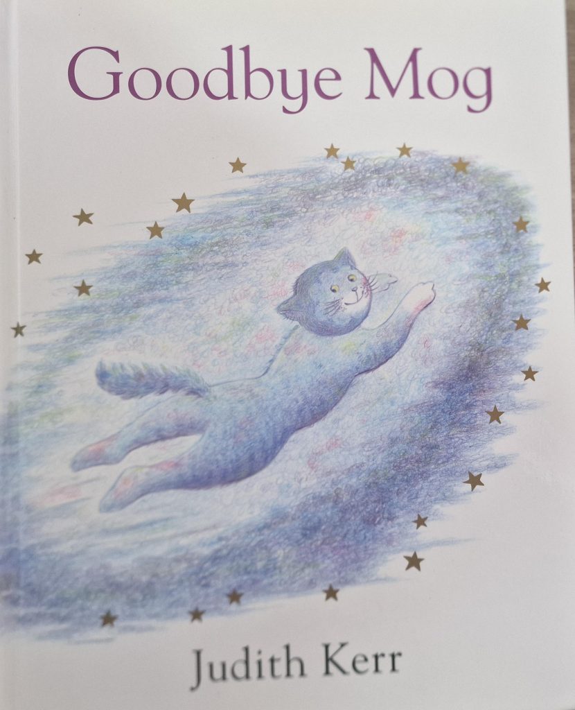 A picture of 'Goodbye Mog' by Judith Kerr. On the cover of the book is a drawing of Mog flying in the air, surrounded by golden stars.
