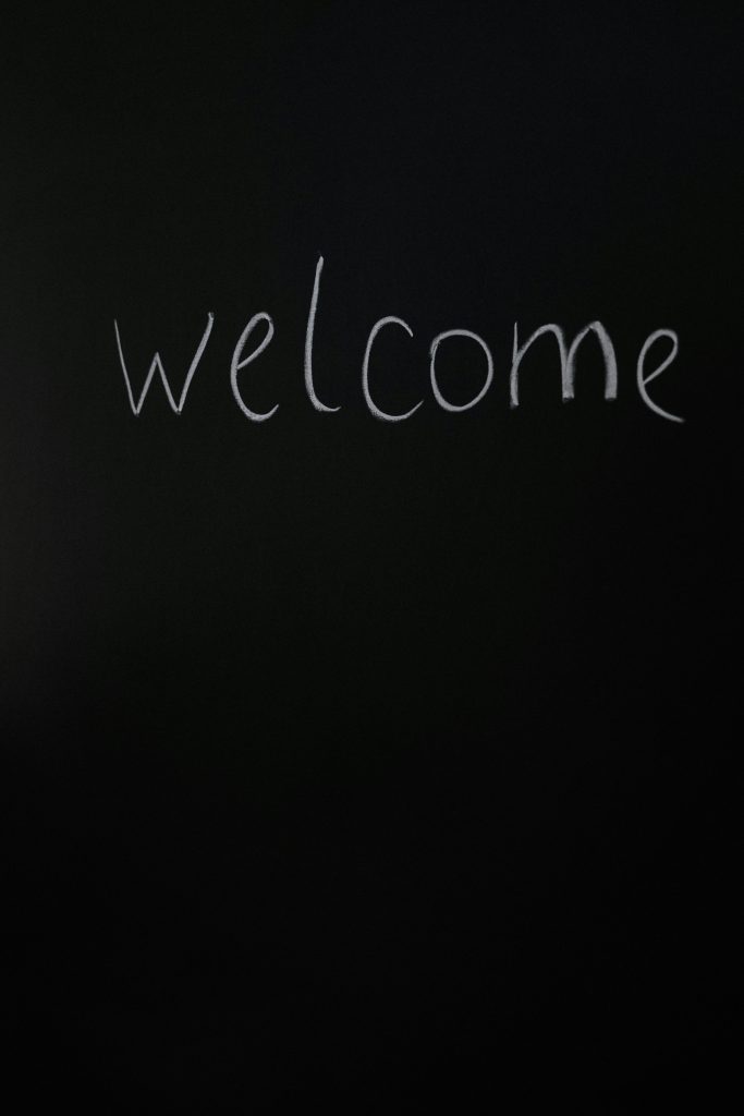 The word 'welcome' is written in white chalk on a blackboard.