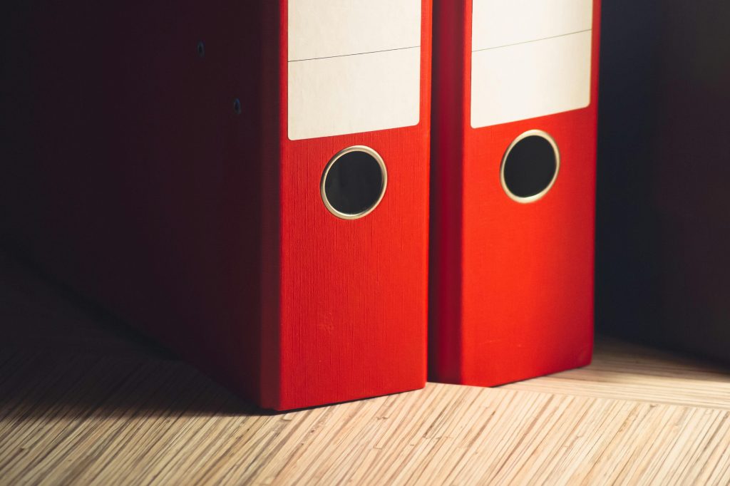 Two red ring-binders on a wooden desk
