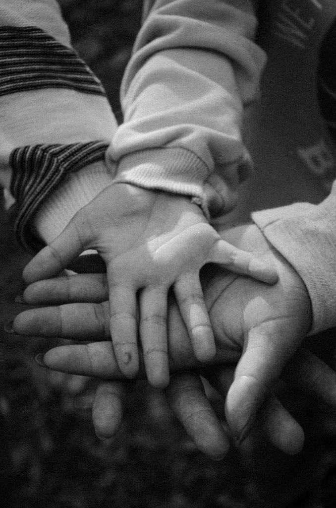 People placing their hands on top of each other's, with a child's hand on top