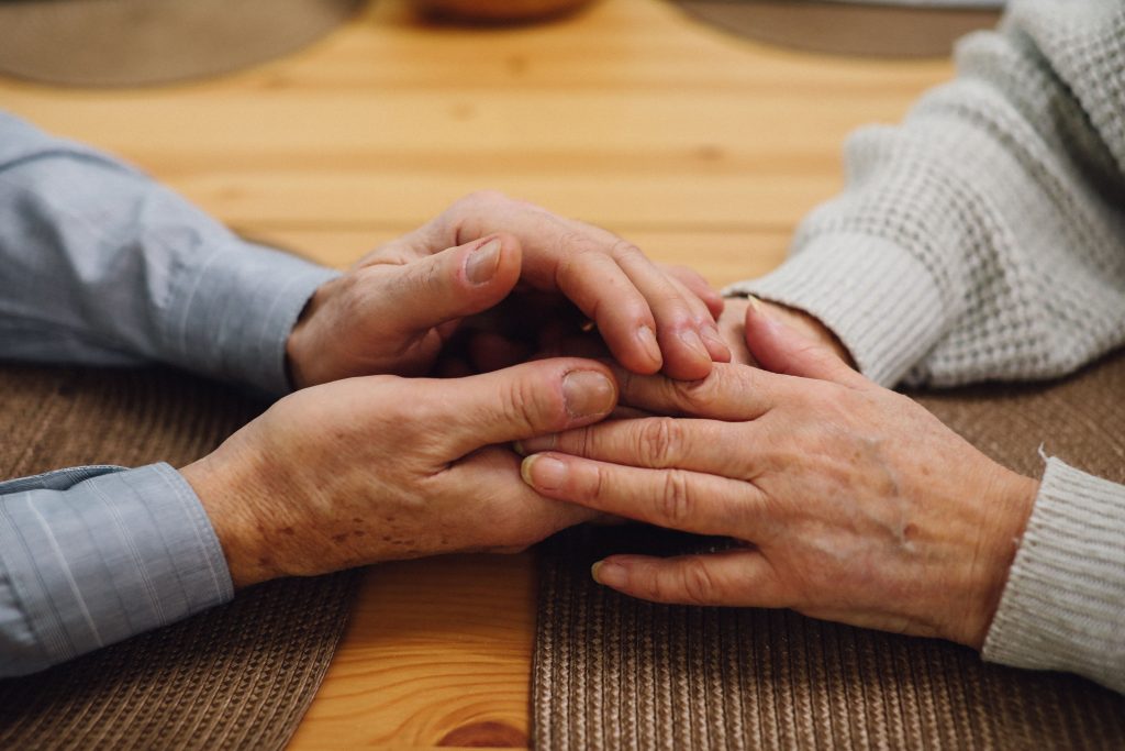 Two people sat opposite each other, holding hands
